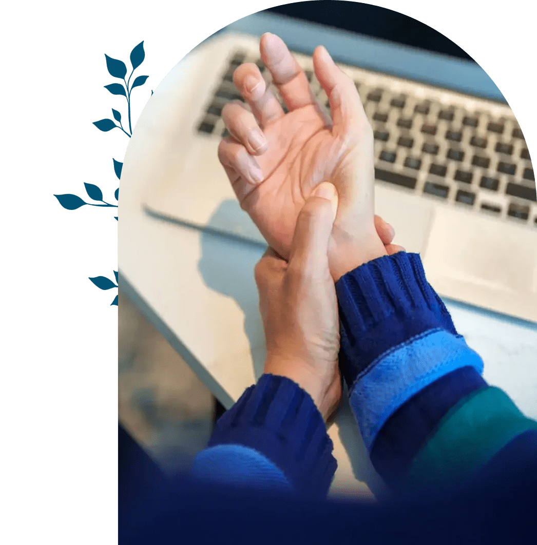 Person holding their wrist in pain near a laptop keyboard.